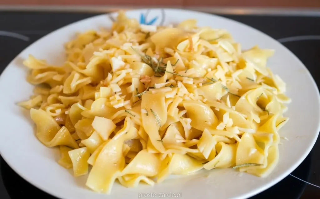 Złocisty makaron tagliatelle z kawałkami świeżego rozmarynu i czosnku, posypany serem.