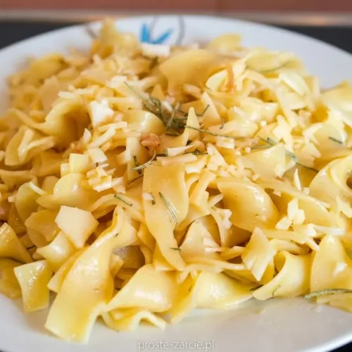 Złocisty makaron tagliatelle z kawałkami świeżego rozmarynu i czosnku, posypany serem.