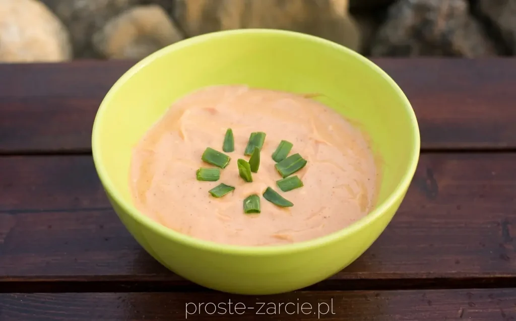 Sos farmera ze szczypiorkiem w małej miseczce, przygotowany jako dodatek do karkówki z grilla.