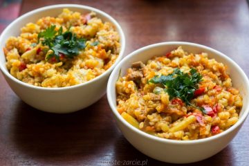 Kolorowe danie w misce – kawałki indyka z ryżem, fasolką szparagową i marchewką w żółtym sosie curry, posypane natką pietruszki.