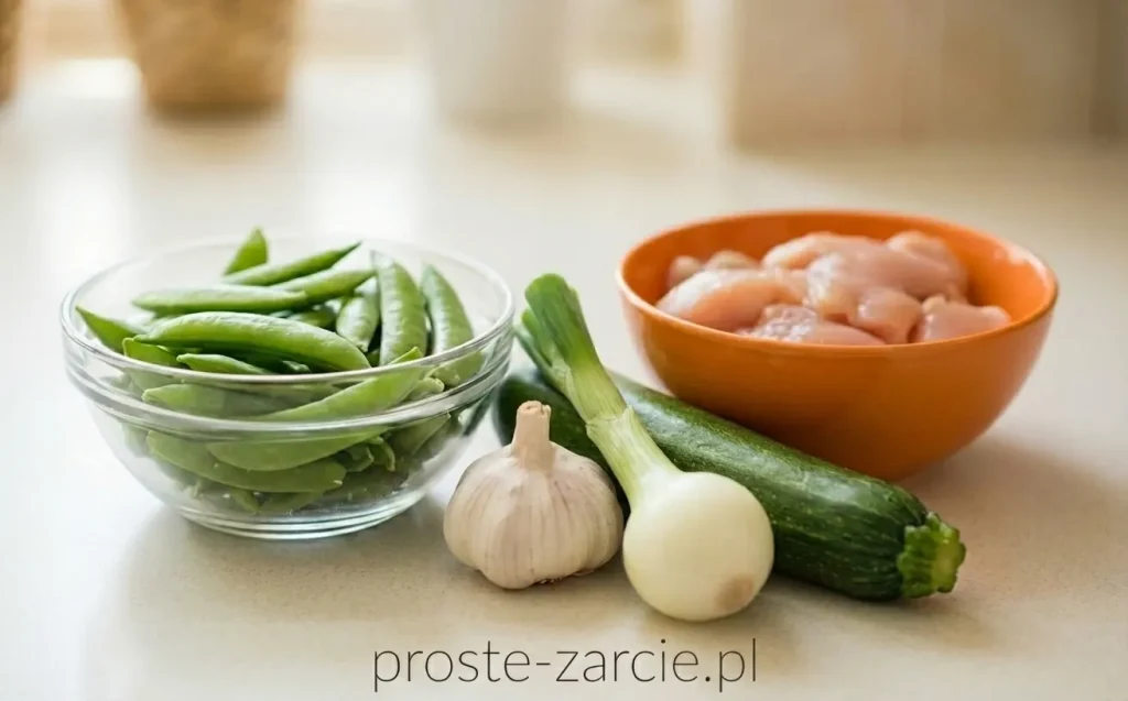 Kremowy makaron spaghetti z zielonymi strączkami groszku cukrowego, kawałkami kurczaka i cukinii, posypany świeżo mielonym pieprzem.