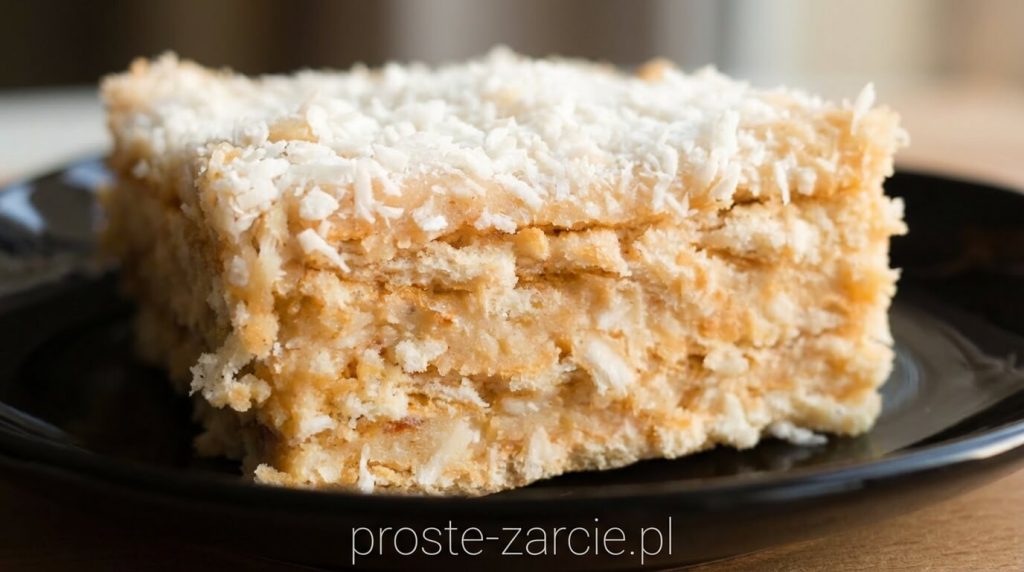 Kwadratowy kawałek białego ciasta rafaello na krakersach z grubą warstwą wiórków kokosowych, proste żarcie