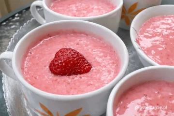 Różowe domowe lody truskawkowe w miseczce udekorowane świeżymi owocami i listkiem mięty