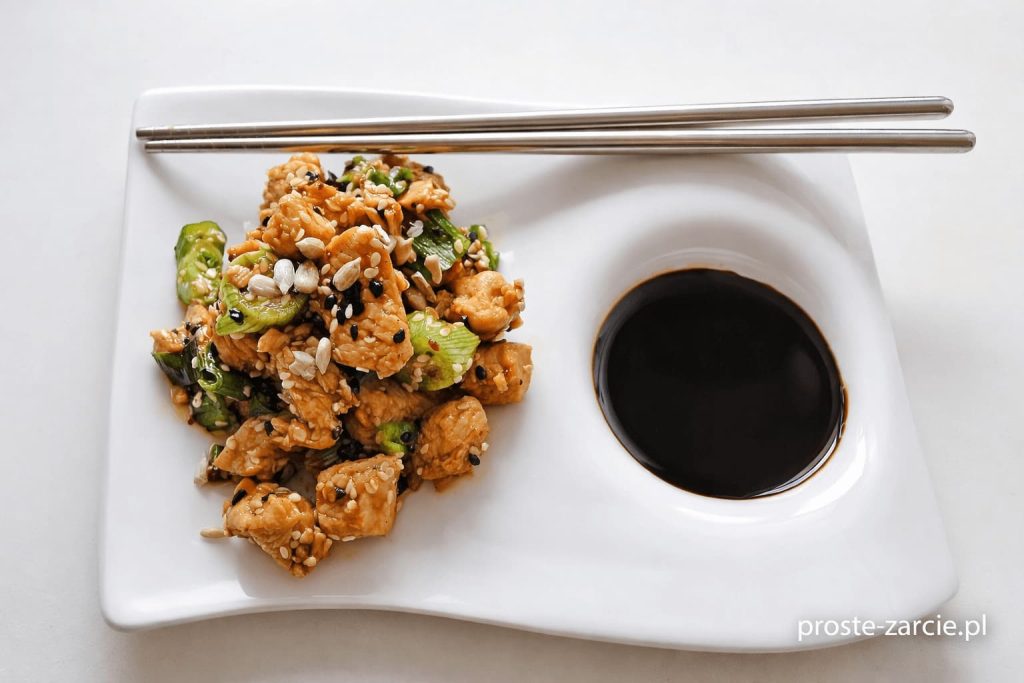 Kawałki indyka w ciemnym sosie teriyaki posypane sezamem podane z ryżem