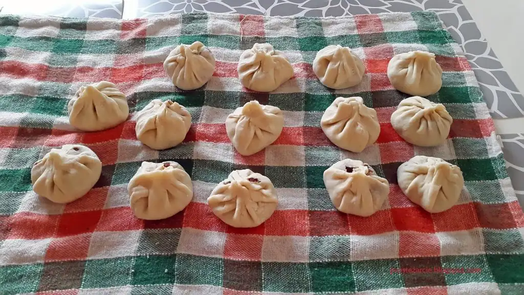 Parujące pierożki wonton w bambusowym koszyczku do gotowania na parze, podane z sosem sojowym.