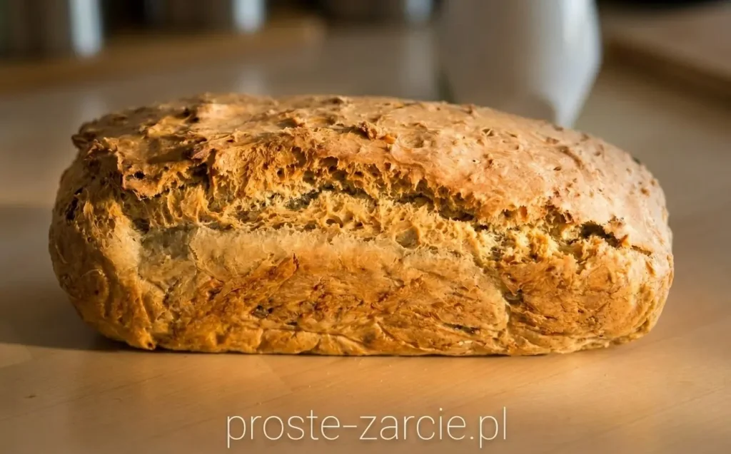 Rumiany domowy chleb z nasionami dyni wyjęty prosto z keksówki, leżący na drewnianej desce.