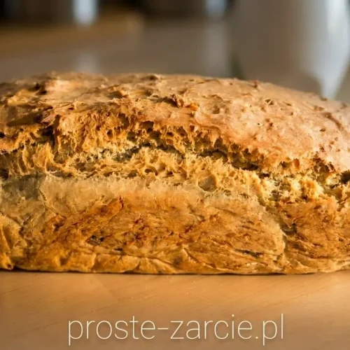 Rumiany domowy chleb z nasionami dyni wyjęty prosto z keksówki, leżący na drewnianej desce.