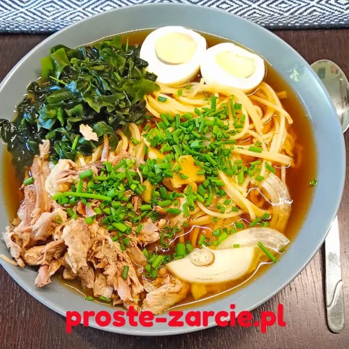 Głęboka miska z ramenem z pieczonej kaczki, makaronem udon, jajkiem na twardo, glonami wakame i szczypiorkiem.
